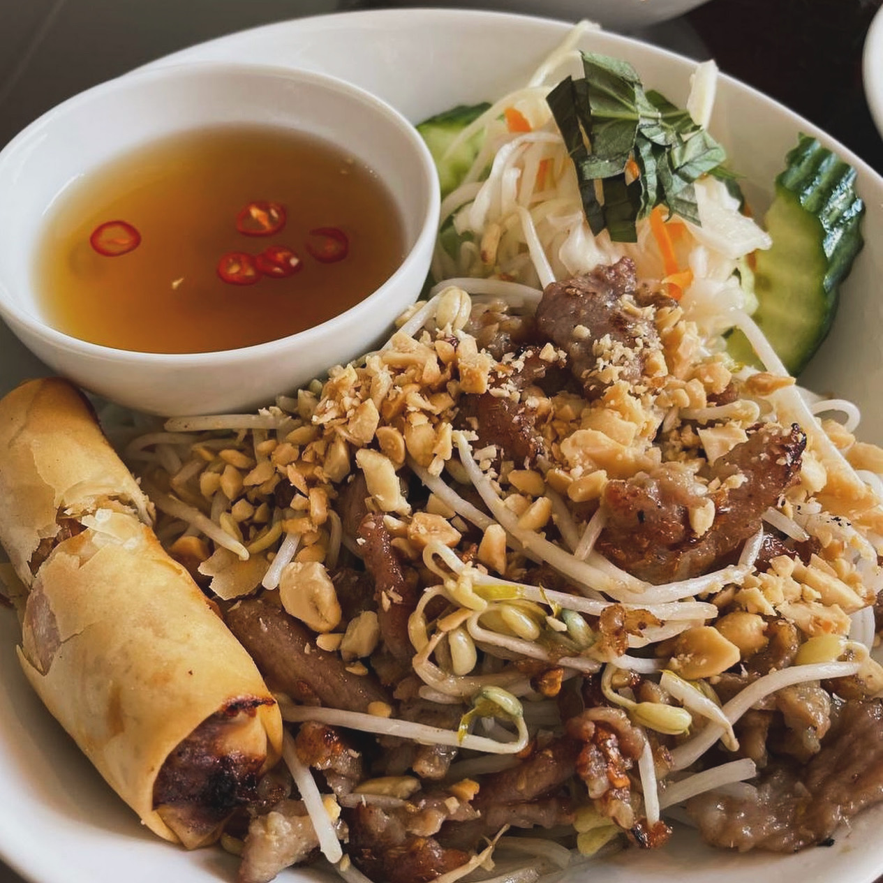 En skål bún bò xào Nam Bộ med risnudlar, nötkött, jordnötter och färska örter