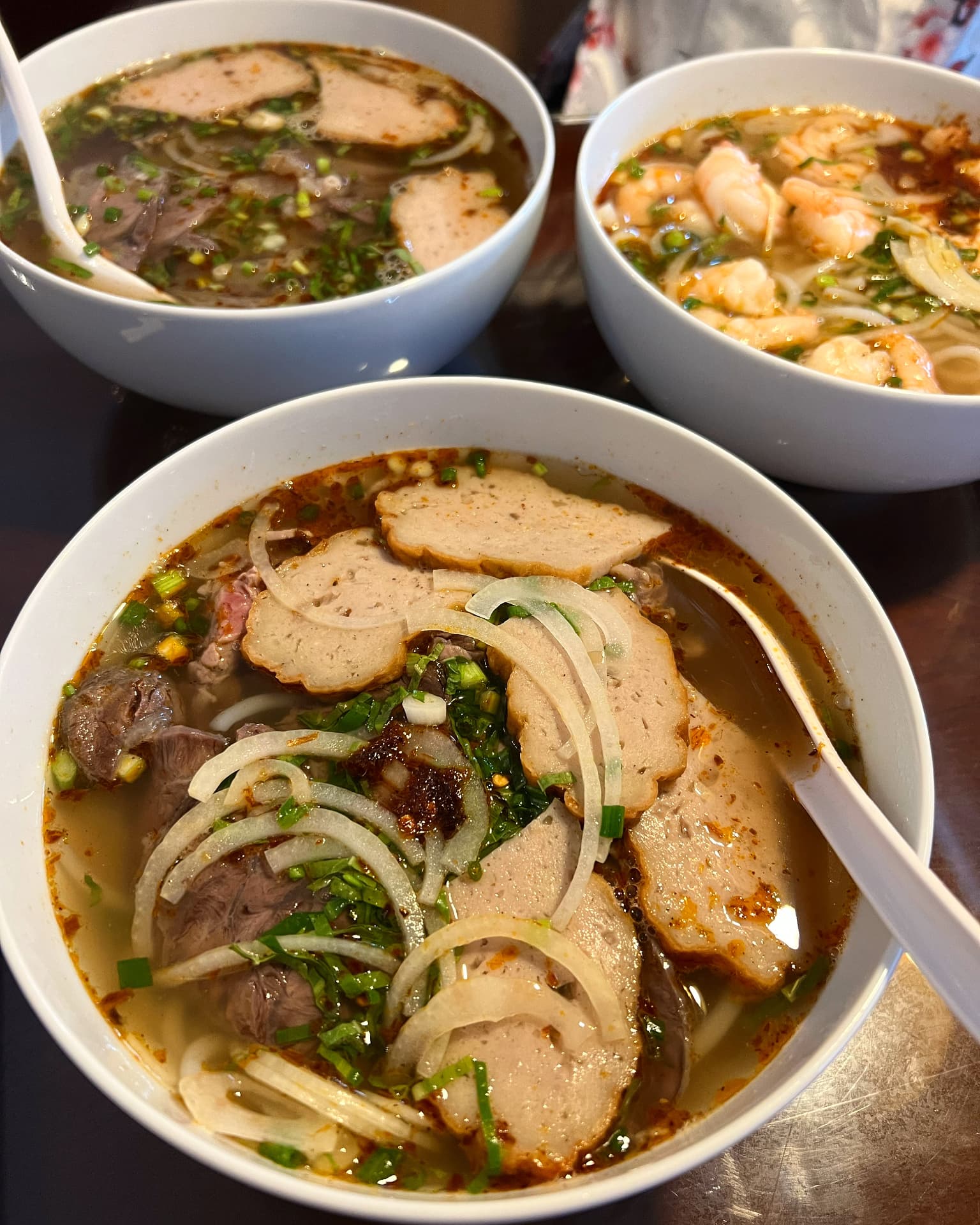 Skålar bún bò Huế med nötkött, risnudlar och färska örter